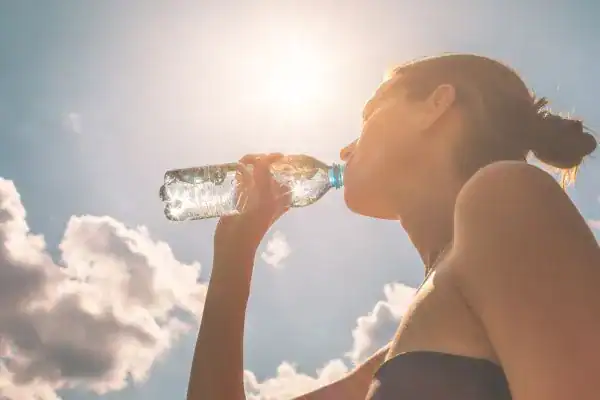 Image of woman drinking water to hydrate Bagshot after run.