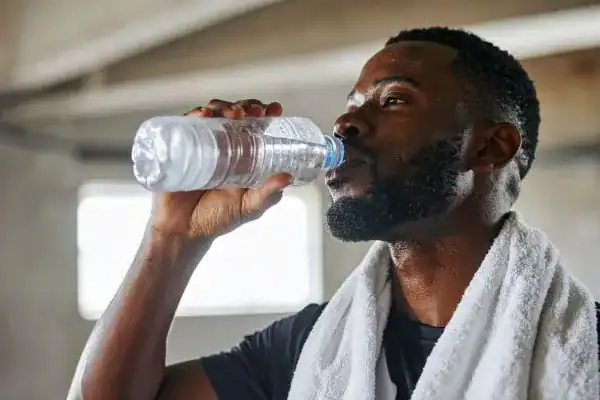Image of man drinking water to improve hydration Bagshot after work out.
